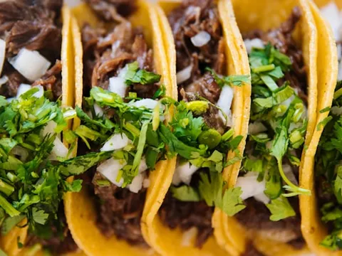 Plate of crispy quesabirria tacos with consomé broth dipping sauce at Tacos El Patron