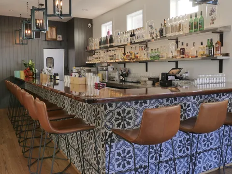 Bar at Dolores in Providence with a blue-and-white Talavera-tiled counter, tan leather stools and shelves of agave spirits