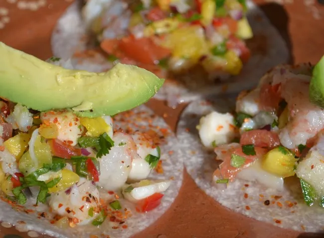 Three ceviche tostadas topped with shrimp, avocado slices, chile powder, and pico de gallo at Machete Tequila + Tacos in Denver