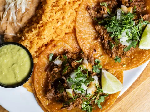 Tacos with a bowl of green salsa at El Beso