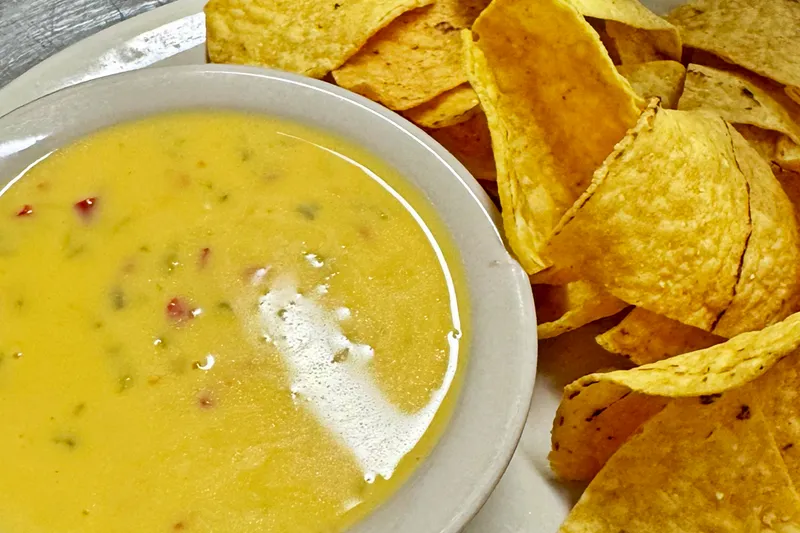 A bowl of chile con queso beside a plate of tortilla chips at Cervantes Restaurant & Lounge in Albuquerque