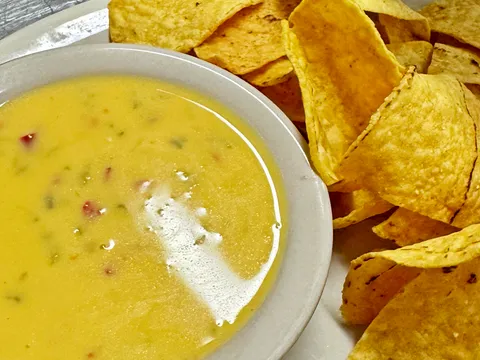A bowl of chile con queso beside a plate of tortilla chips at Cervantes Restaurant & Lounge in Albuquerque