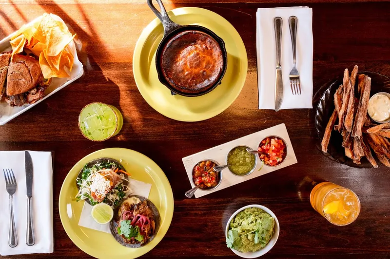 Overhead spread at Vida Cantina with a cast-iron cheese fundido, blue-corn tacos, a three-salsa flight, guacamole, sweet potato fries and margaritas