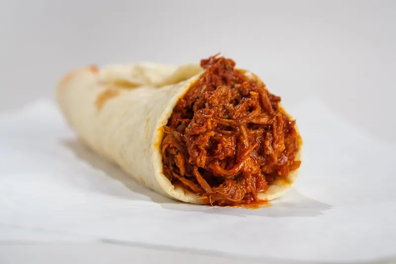 A carne adovada burrito filled with red chile shredded pork in a flour tortilla on paper at Golden Pride in Albuquerque