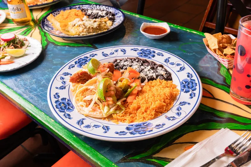 A fish taco plate with Mexican rice and black beans on a hand-painted Talavera table at El Metate Restaurant in San Francisco