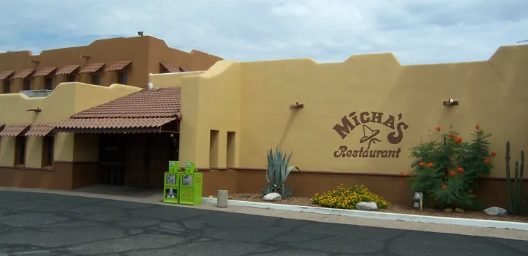 The tan adobe-style exterior of Micha's Restaurant in South Tucson with the 'Micha's Restaurant' name painted on the wall and agave and desert landscaping out front