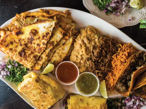 Quesabirria tacos and consomme on a platter at Chucho's Red Tacos